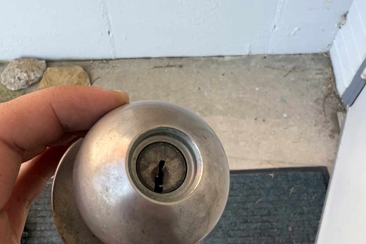 A locksmith inspecting the keyway of a residential knob lock