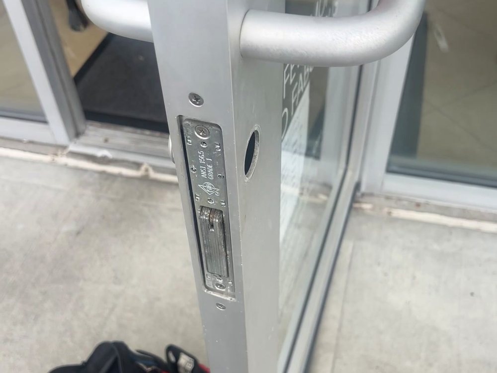 An aluminium storefront door with the lock body and strike exposed